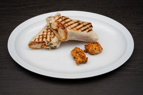 Chicken Tawook Sandwich A white plate topped with a grilled wrap and chicken pieces.