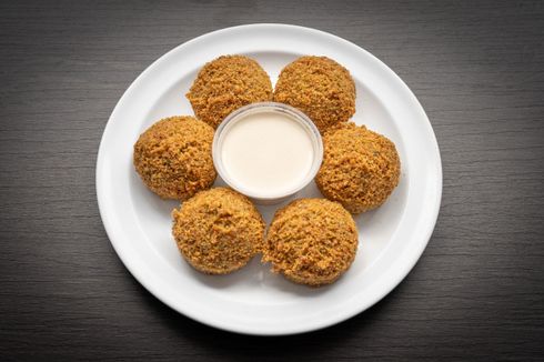 Falafel A white plate topped with falafel balls and a dipping sauce.
