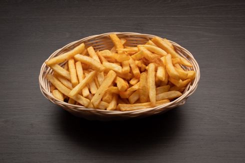 fries A basket of french fries is sitting on a wooden table.