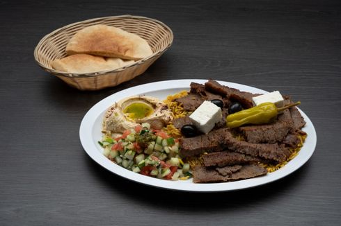 Gyro Plate A plate of food with a basket of bread in the background.