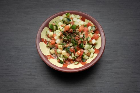 House Salad A bowl of salad with tomatoes and cucumbers on a table.