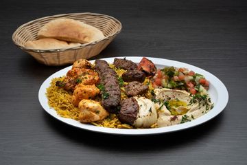 A plate of food with a basket of bread in the background.