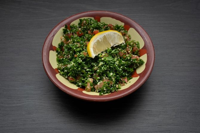 Tabbouleh Salad A bowl of food with a slice of lemon on top.