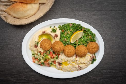 Vegetarian Plate A plate of food with falafel , hummus , and vegetables on a table.