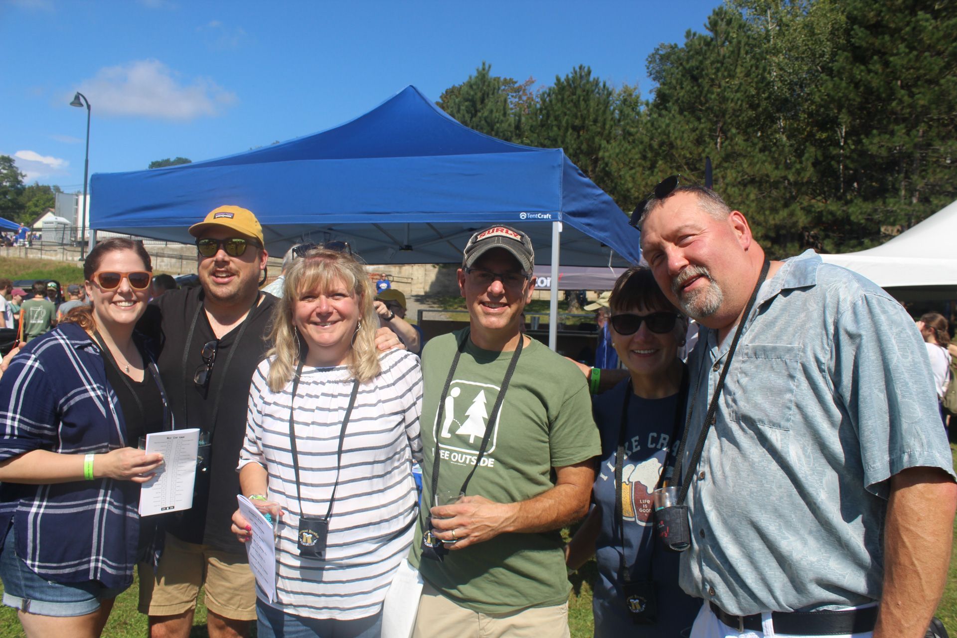 A group of people are posing for a picture in front of a blue tent.