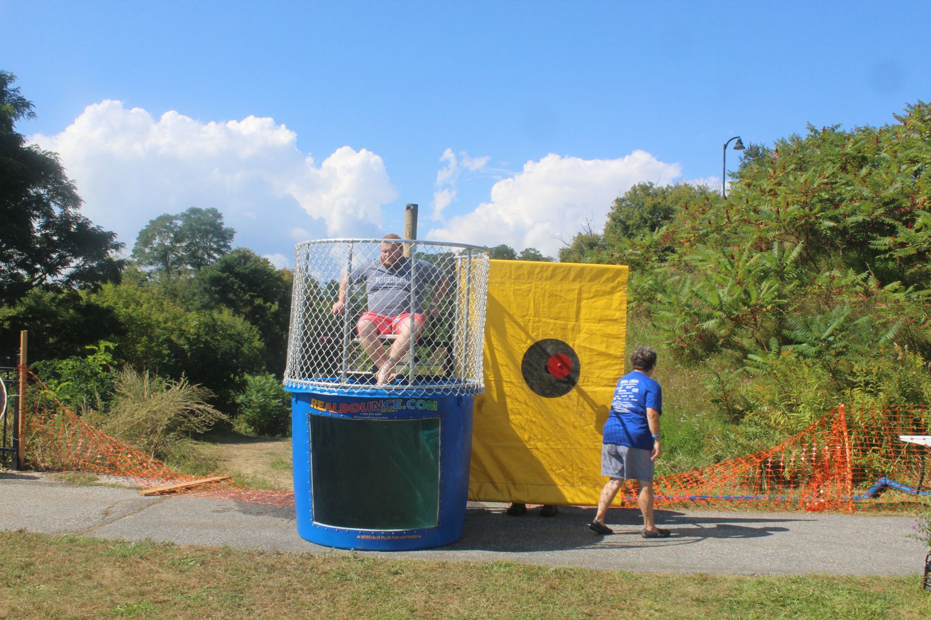 A man is sitting in a dunk tank next to a yellow target.