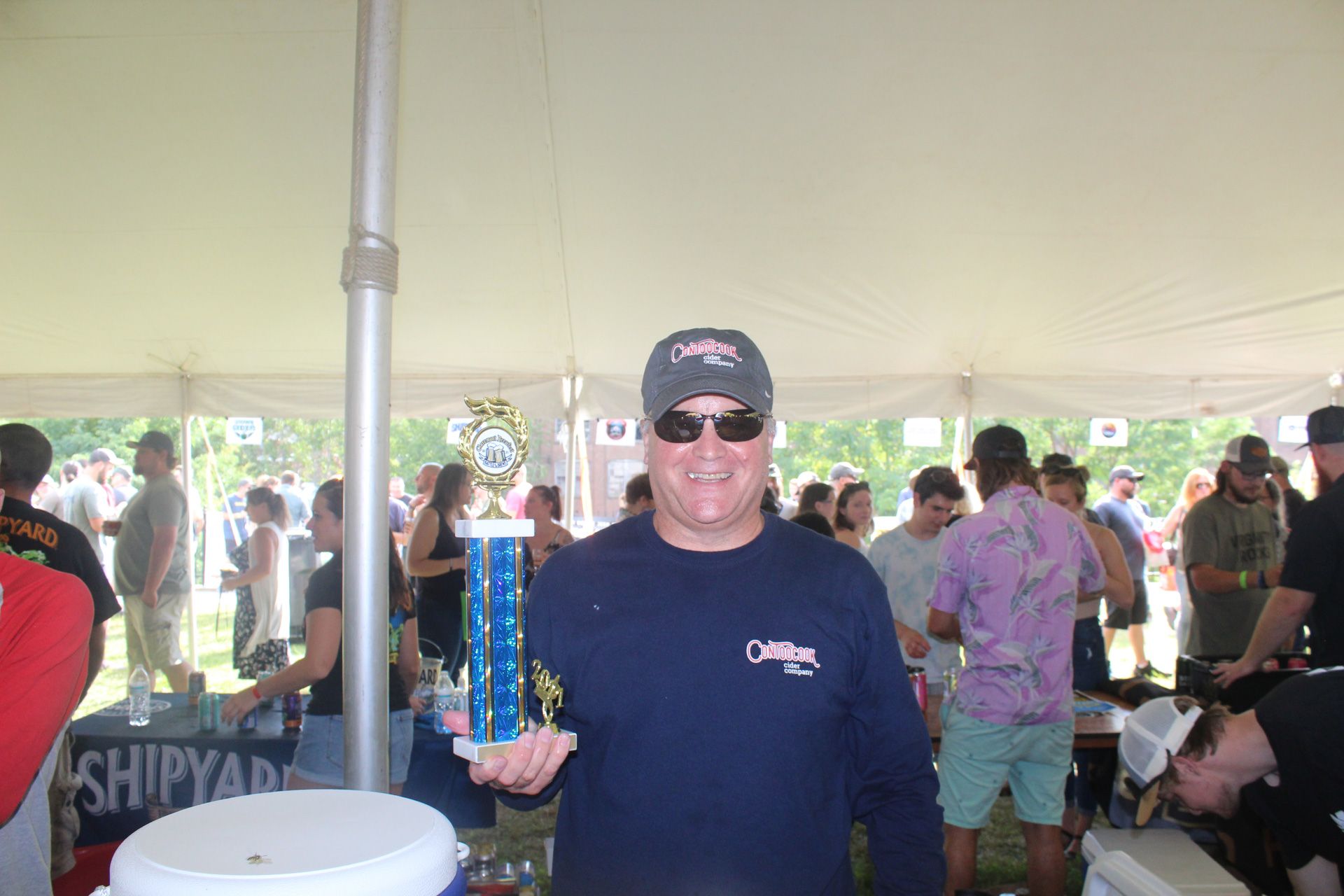 A man in a blue shirt is holding a trophy