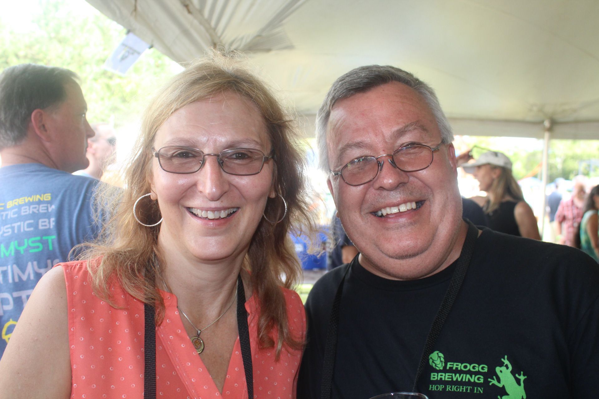A man and a woman are posing for a picture under a tent.