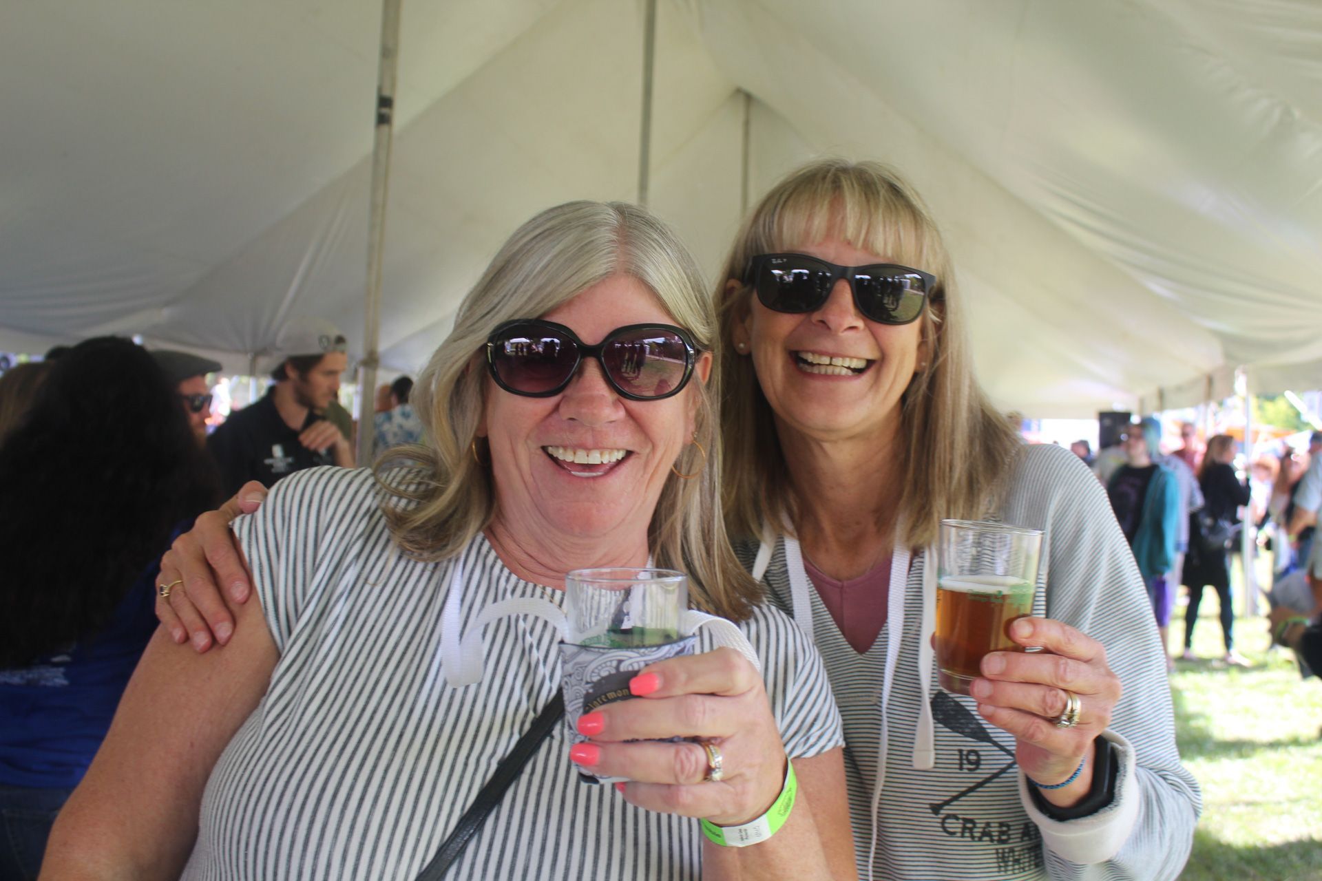 Two women are standing next to each other holding glasses of beer.