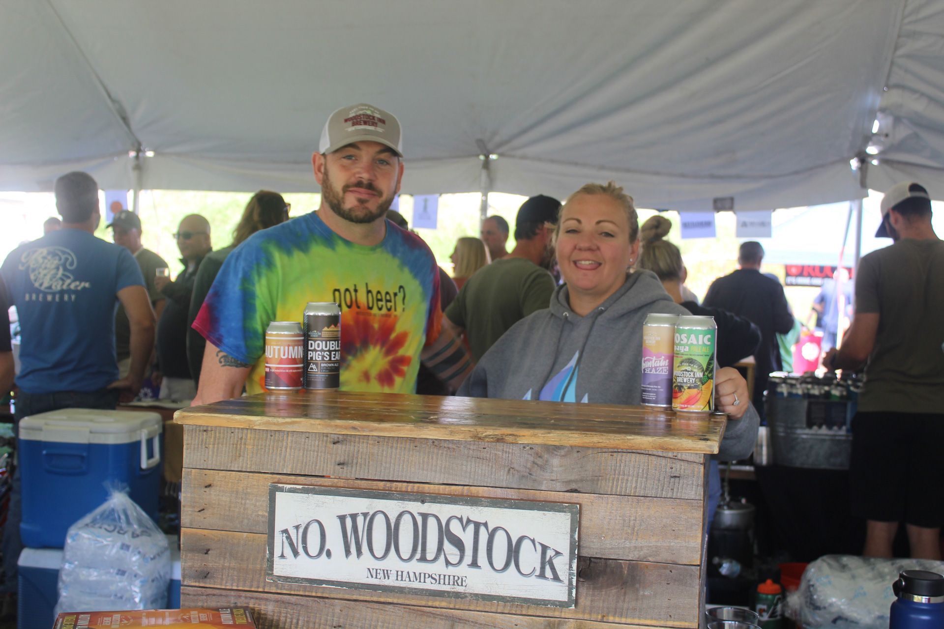 A man and a woman are standing behind a no woodstock sign