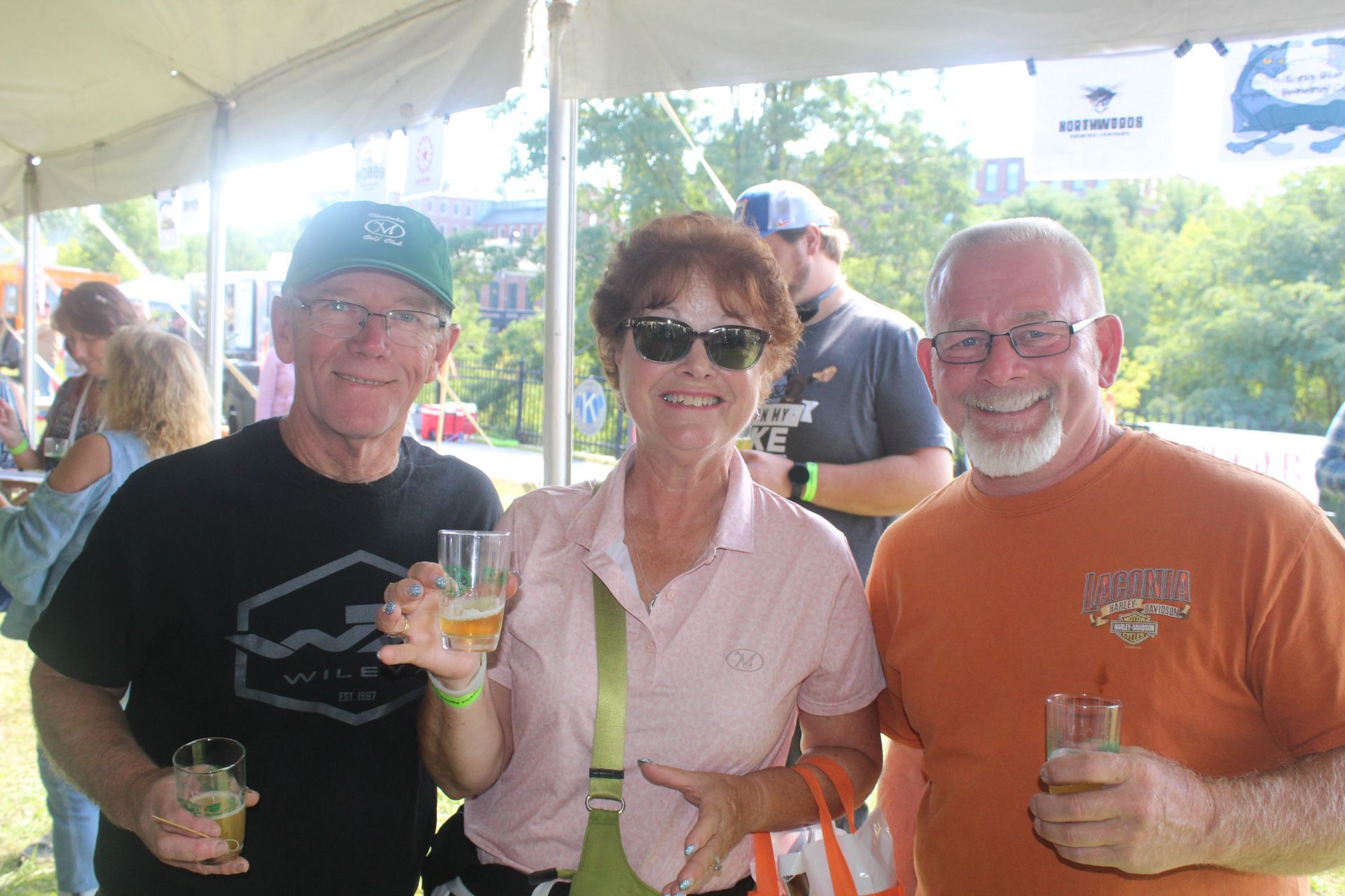 A group of people are standing under a tent holding drinks.