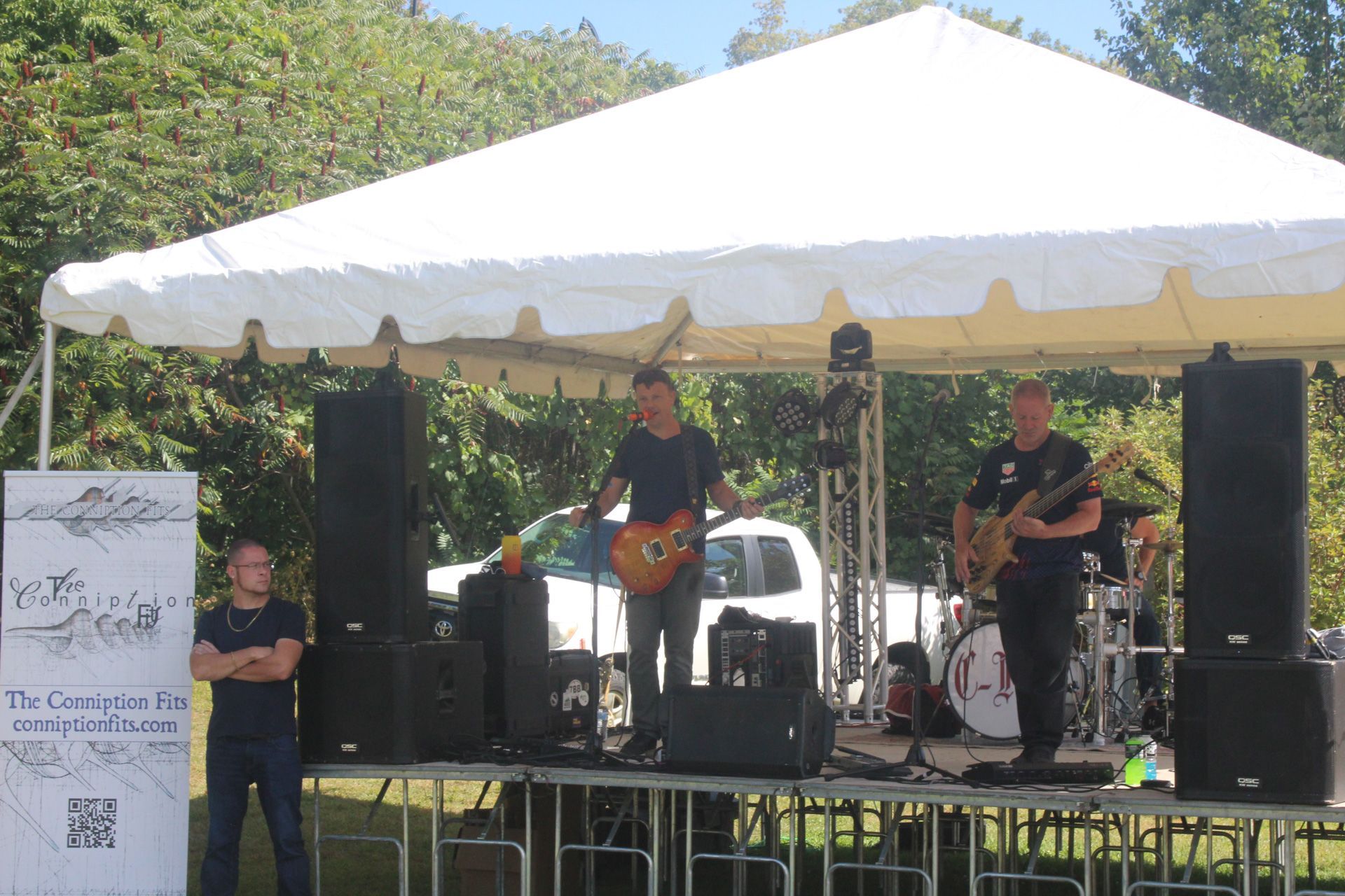 A man playing a guitar on a stage under a white tent