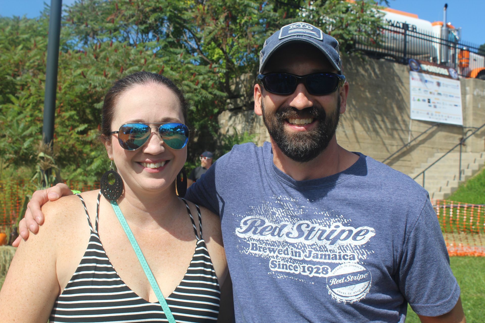 A man and a woman are posing for a picture and the man is wearing a red stripe shirt