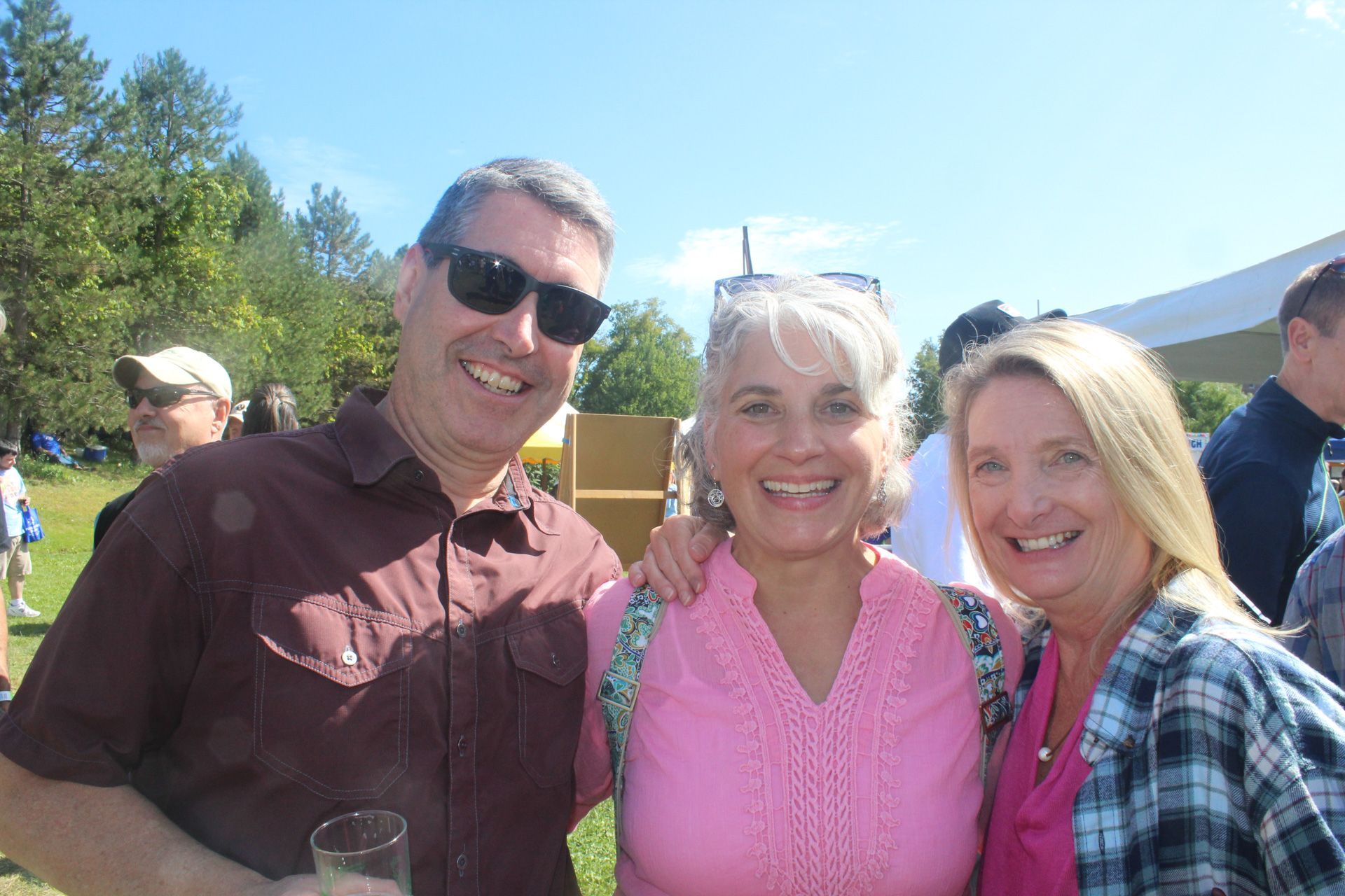 A man and two women are posing for a picture in a park.