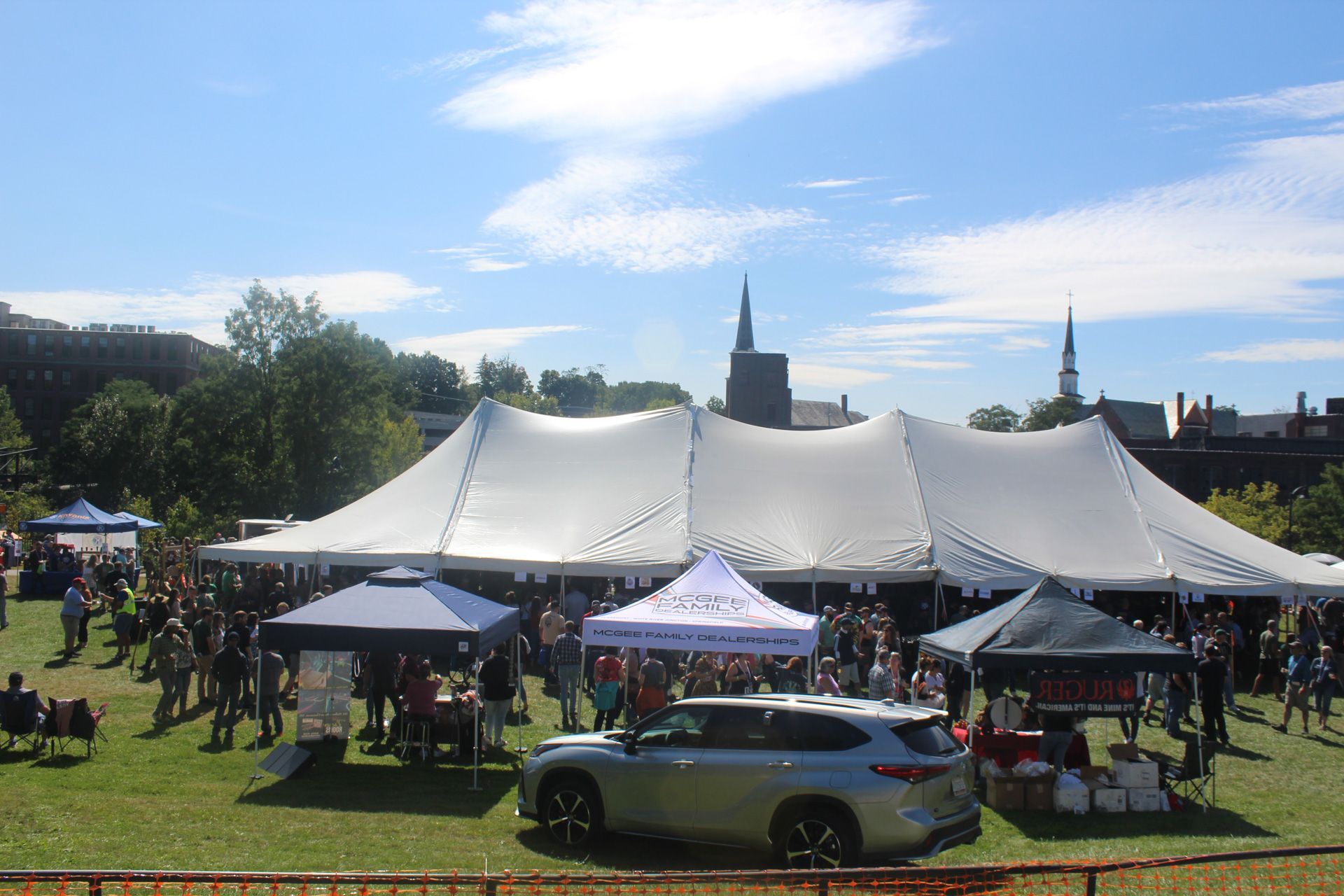 A car is parked in front of a large tent at a festival.