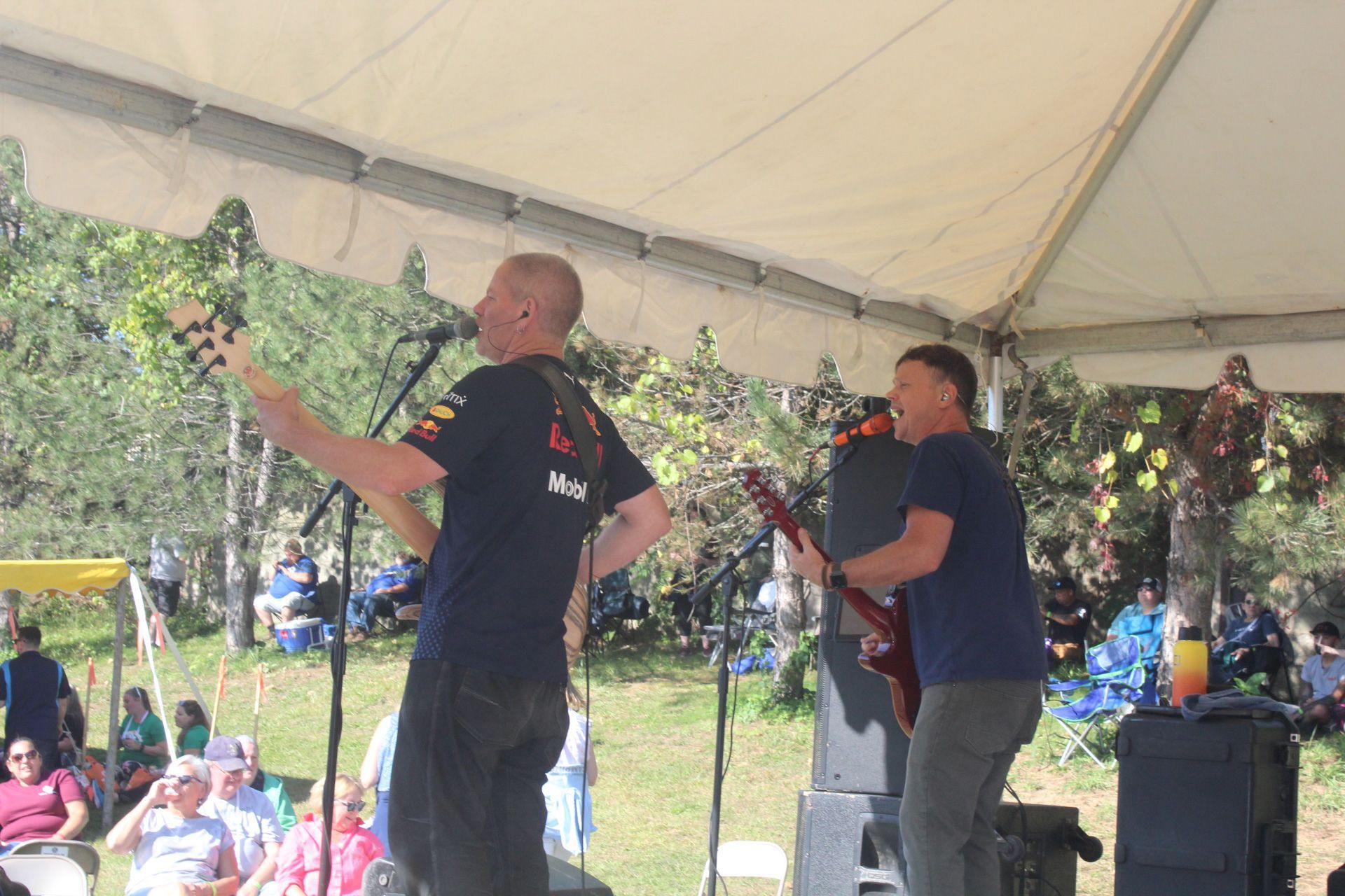 Two men are playing guitars and singing into microphones on a stage.
