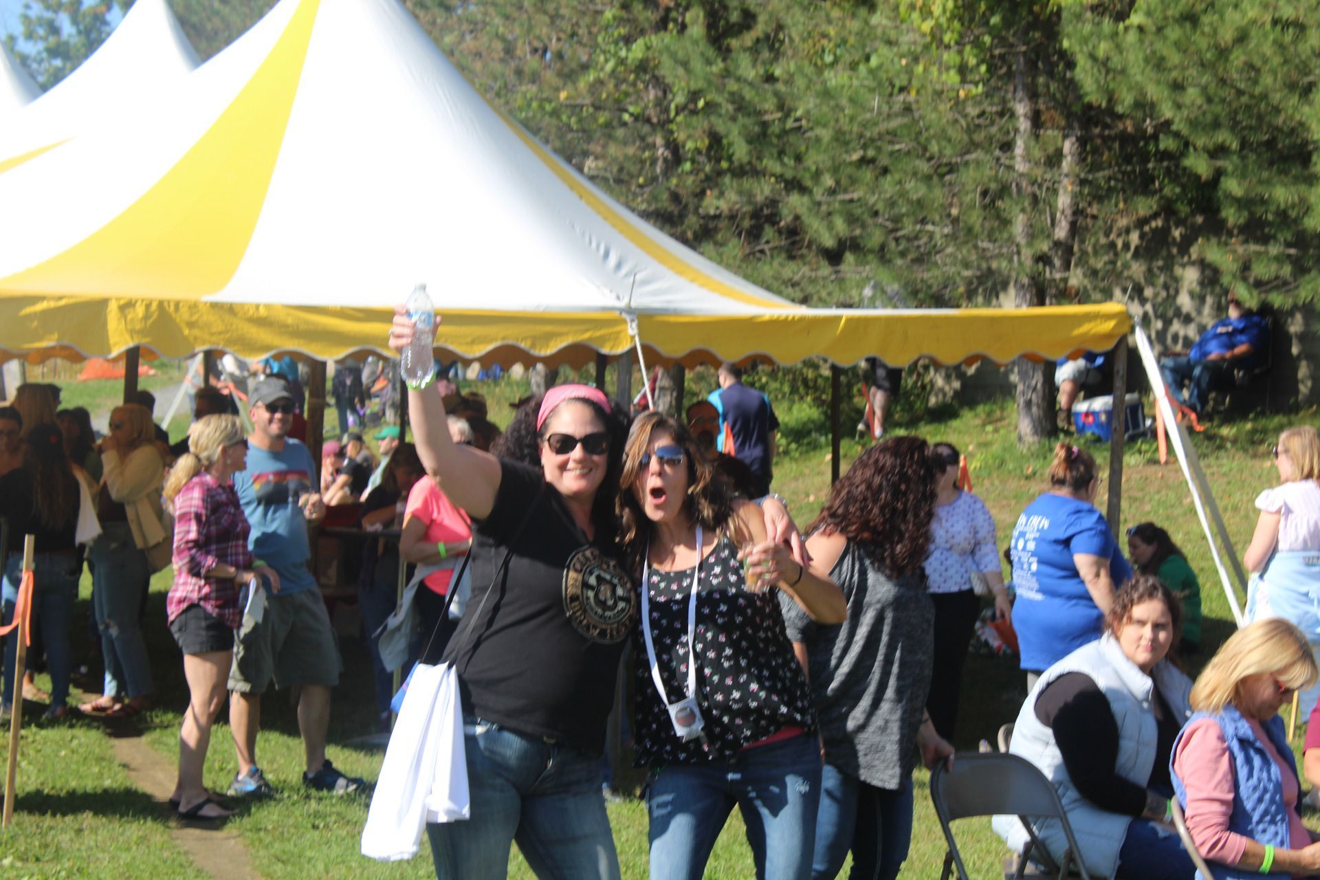 A group of people are standing under a yellow and white tent.