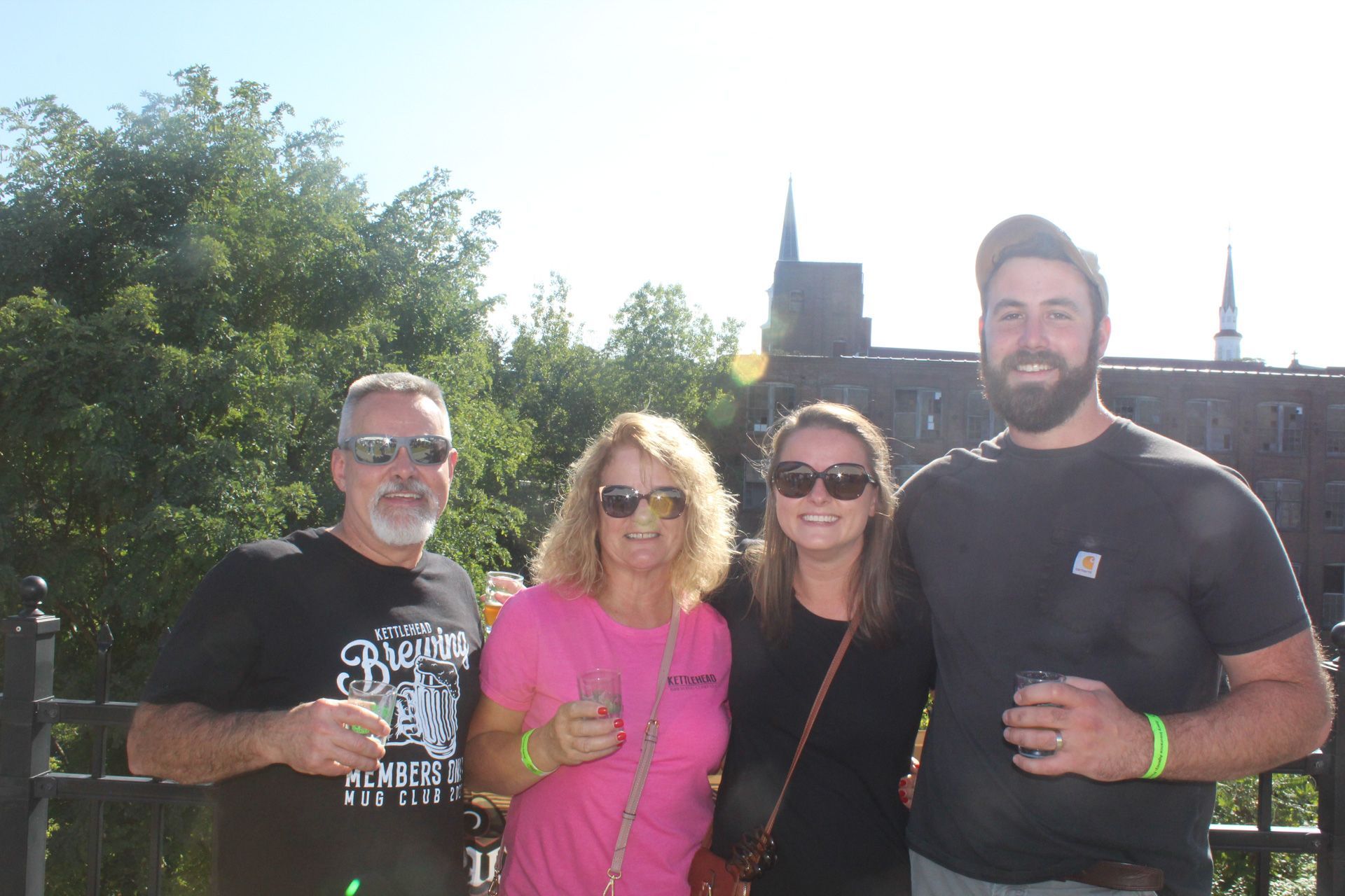 A group of people posing for a picture with a man wearing a shirt that says ' brew ' on it