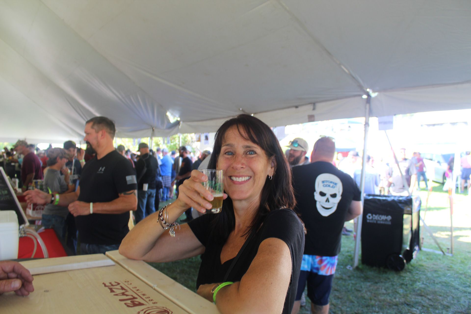 A woman is sitting at a table with a glass of beer in her hand.