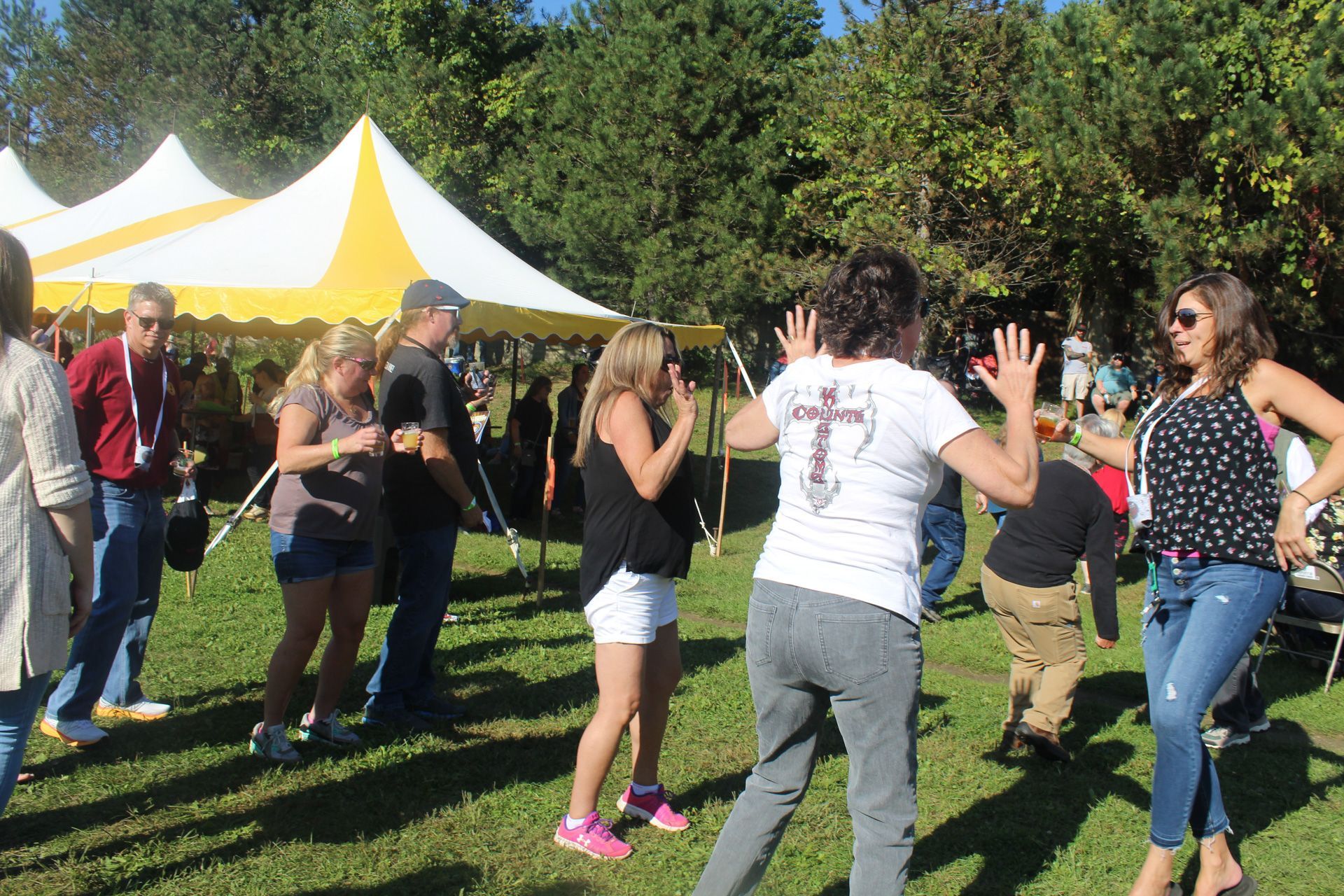 A group of people are dancing in the grass in front of a tent.