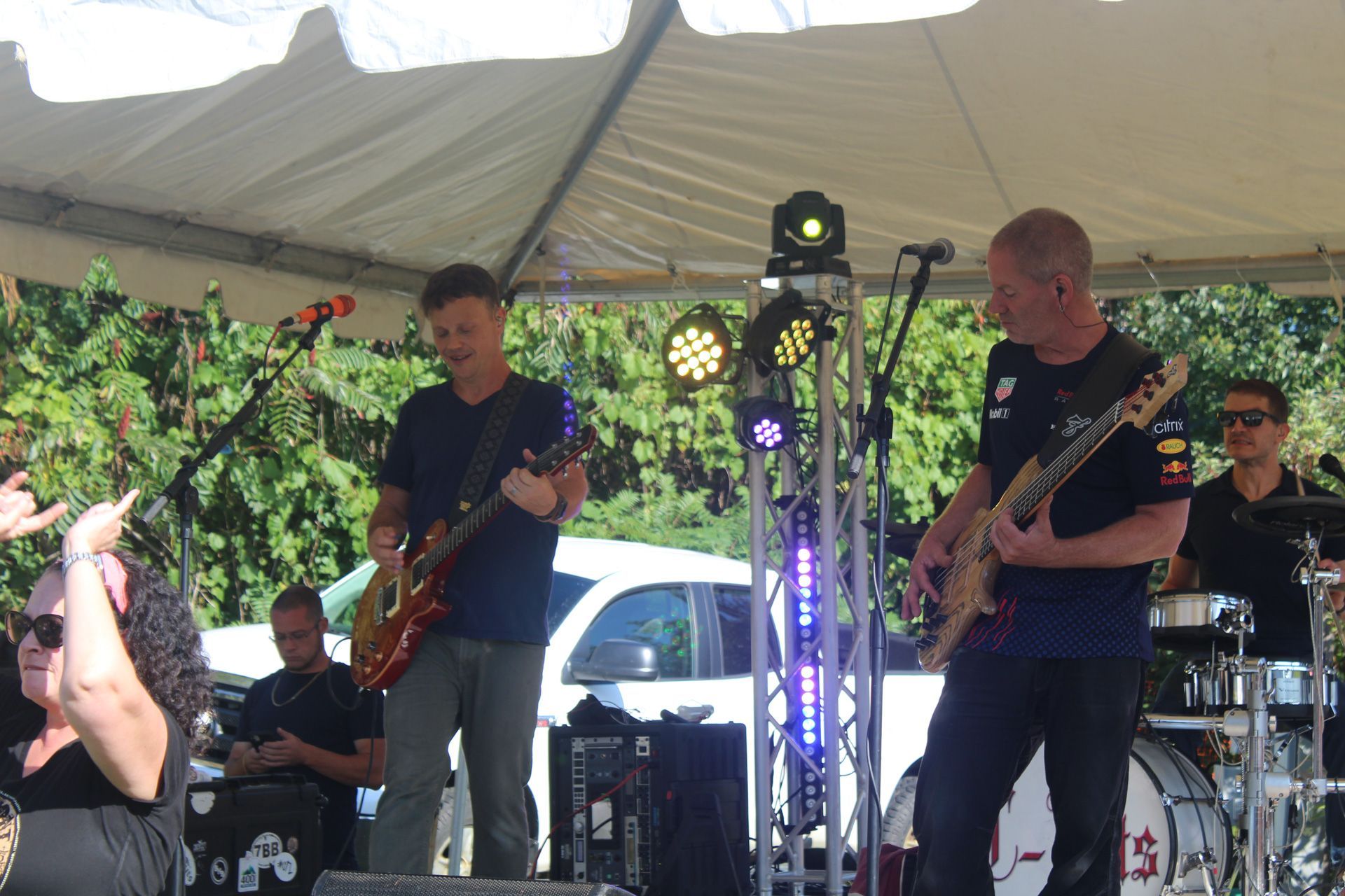 A group of men are playing guitars on a stage under a tent.