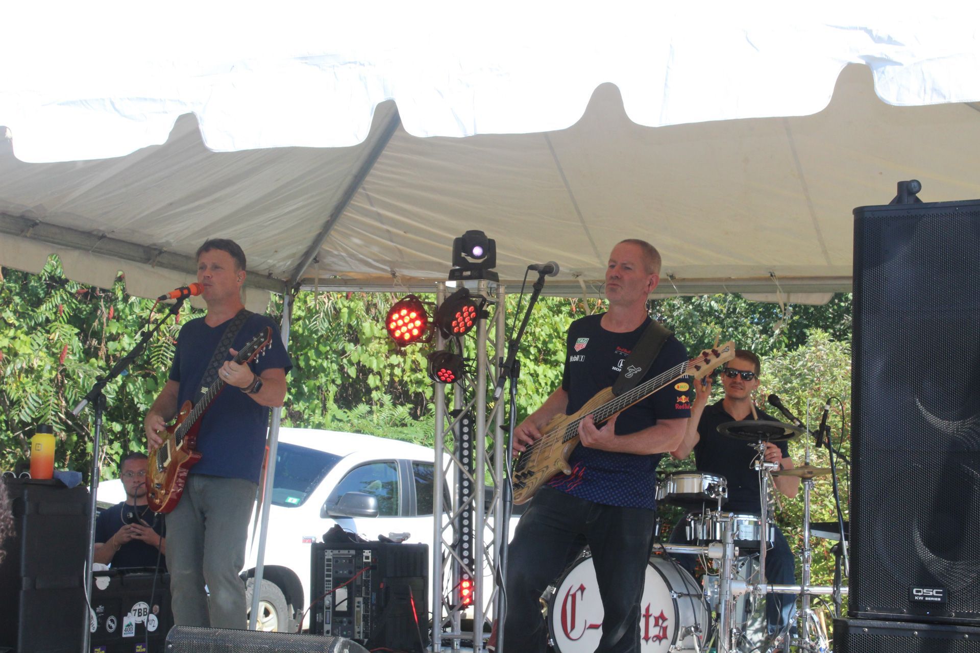 A group of men are playing guitars and singing on a stage under a tent.