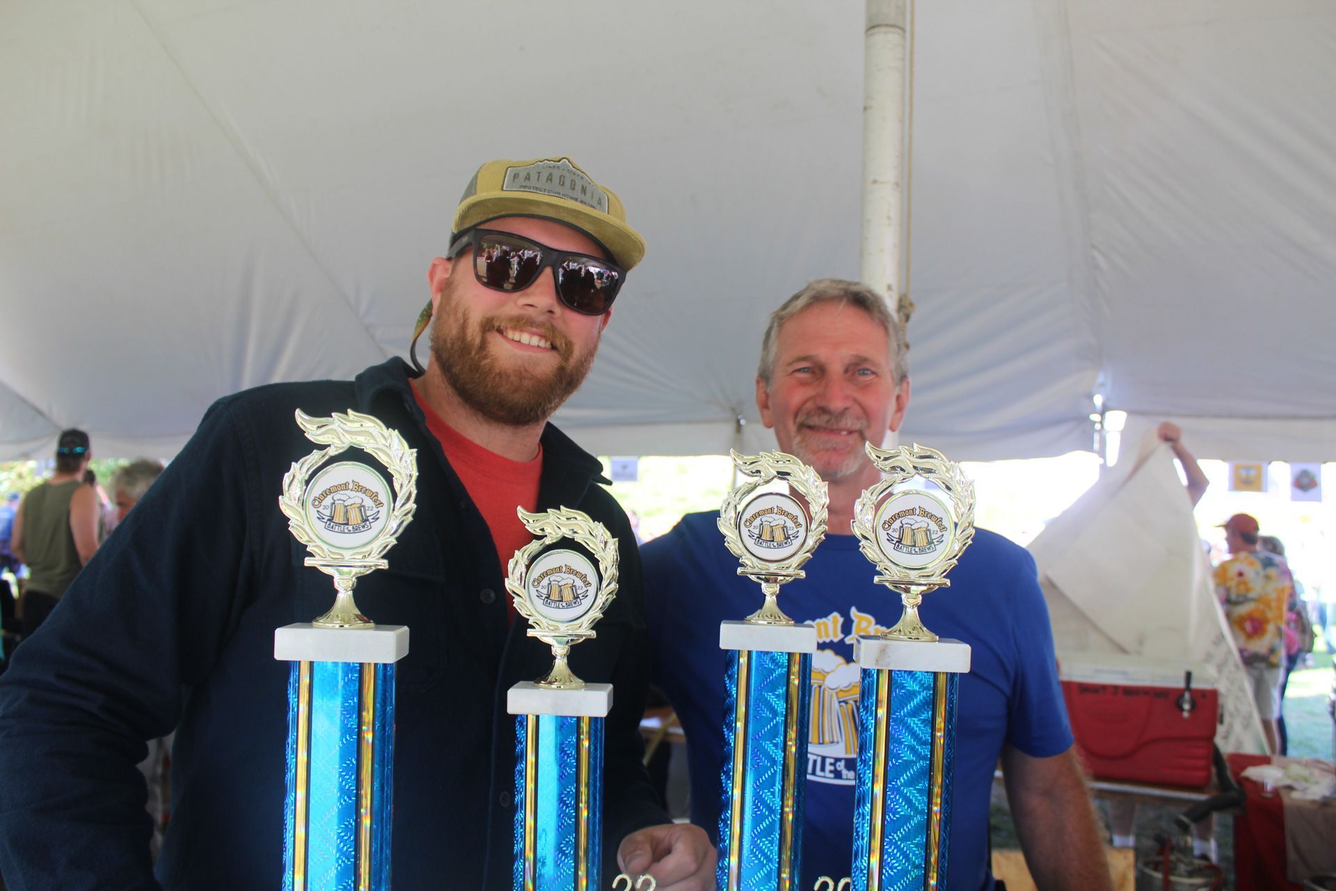 Two men are standing next to each other holding trophies.