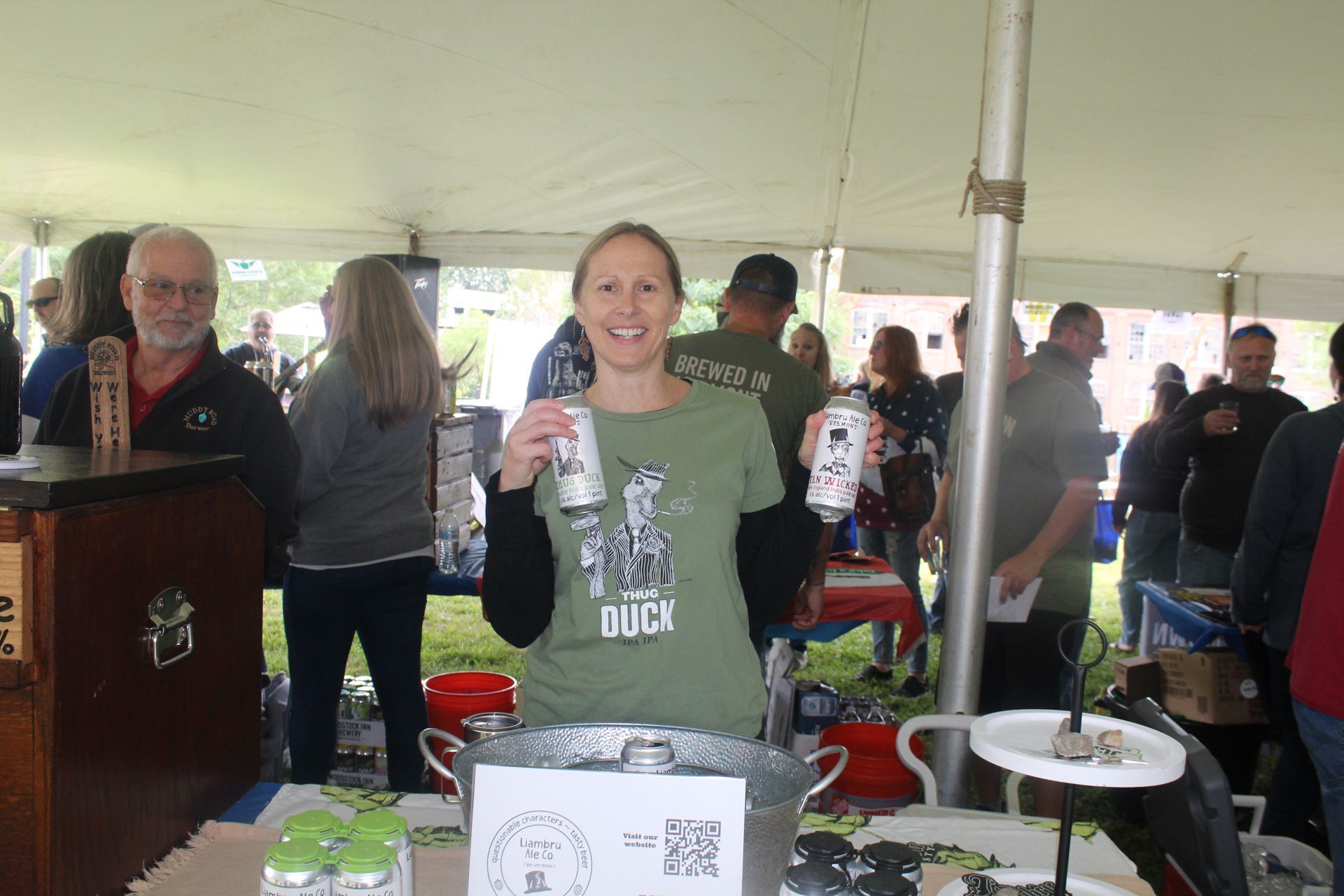 A woman in a green shirt is holding a can of beer.