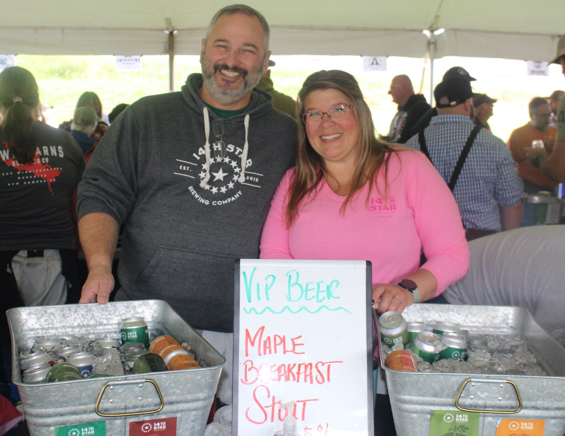 A man and woman standing next to a sign that says maple breakfast stout