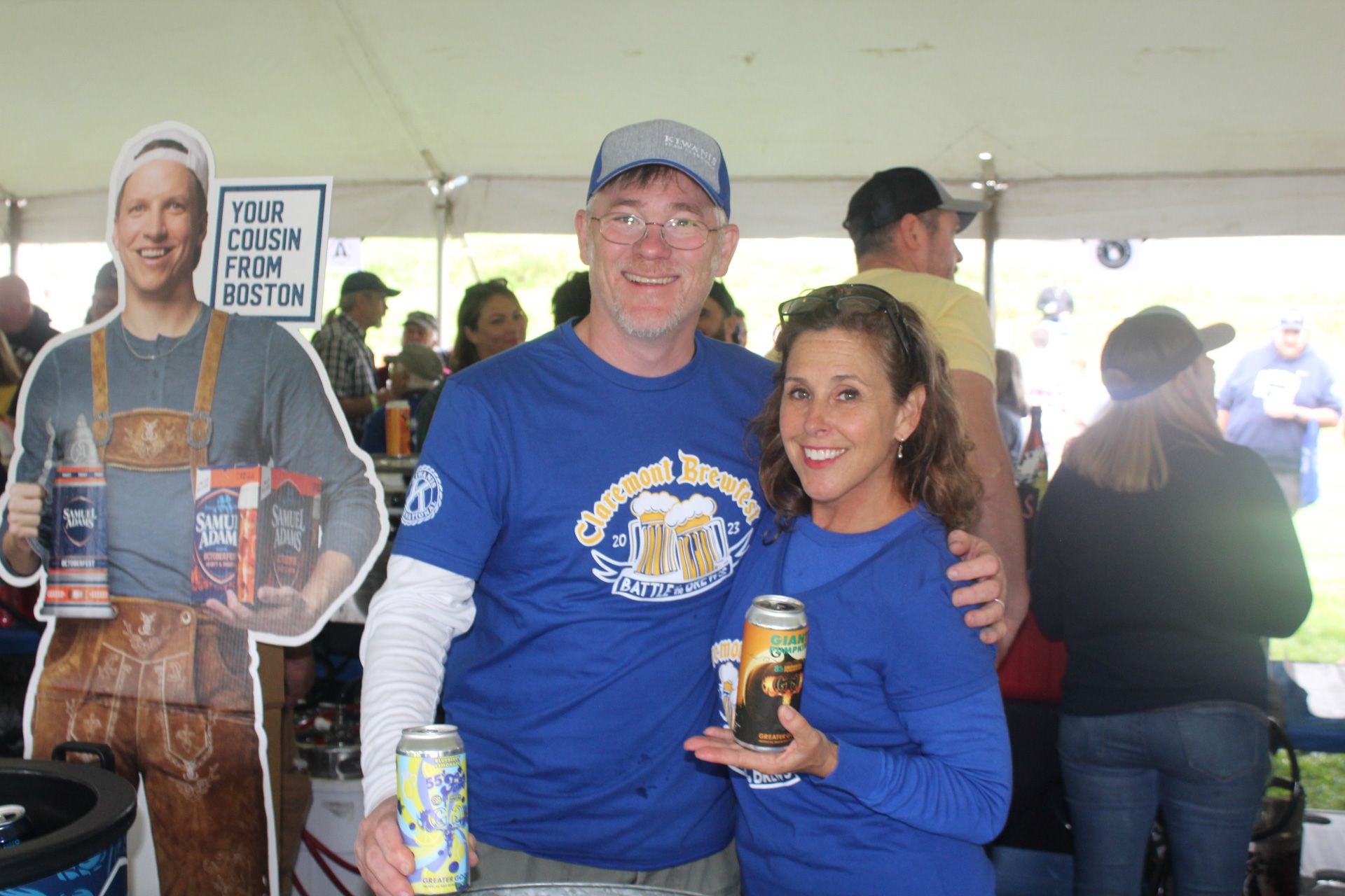 A man and a woman are posing for a picture while holding cans of beer