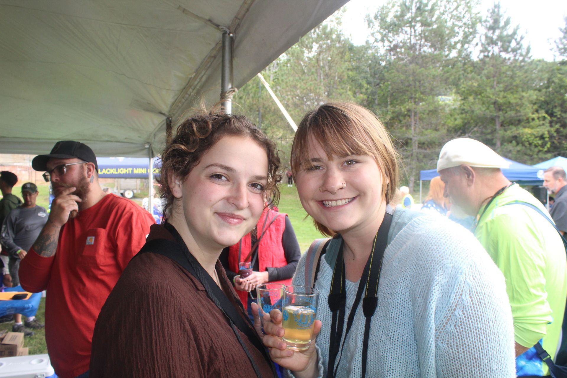 Two women are posing for a picture while holding glasses of beer.