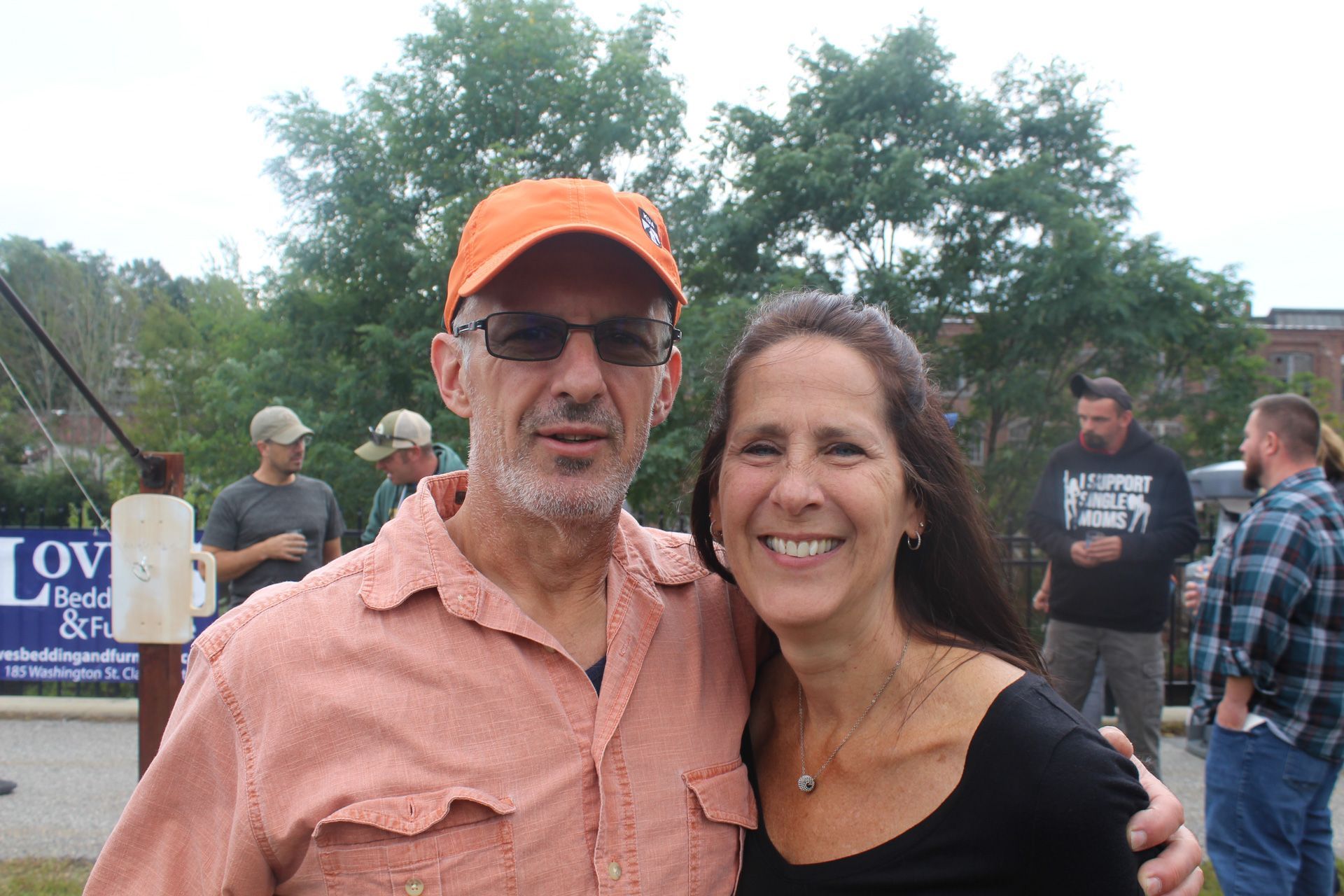 A man and a woman are posing for a picture in front of a sign that says love