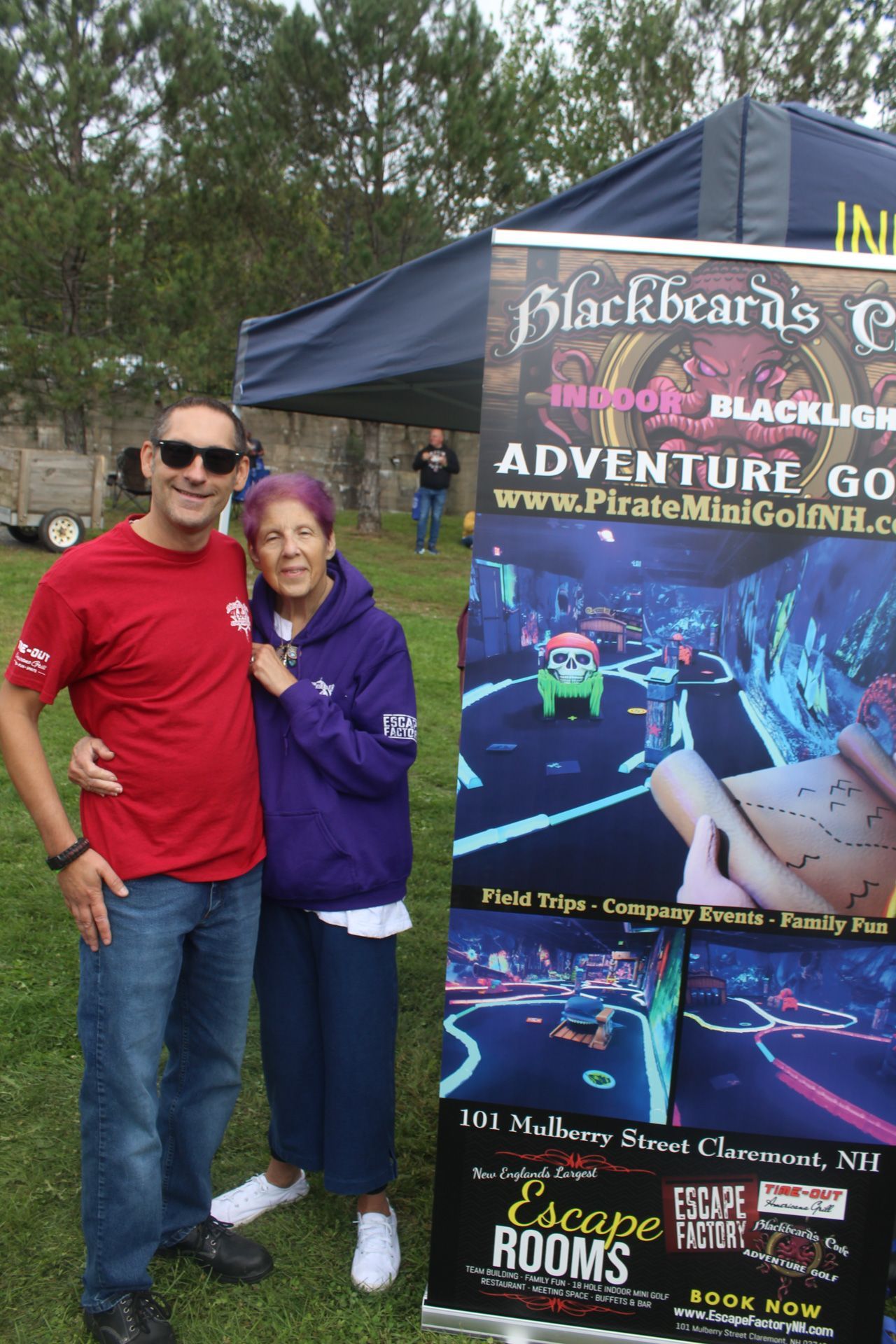 A man and woman are posing for a picture in front of a sign that says adventure go