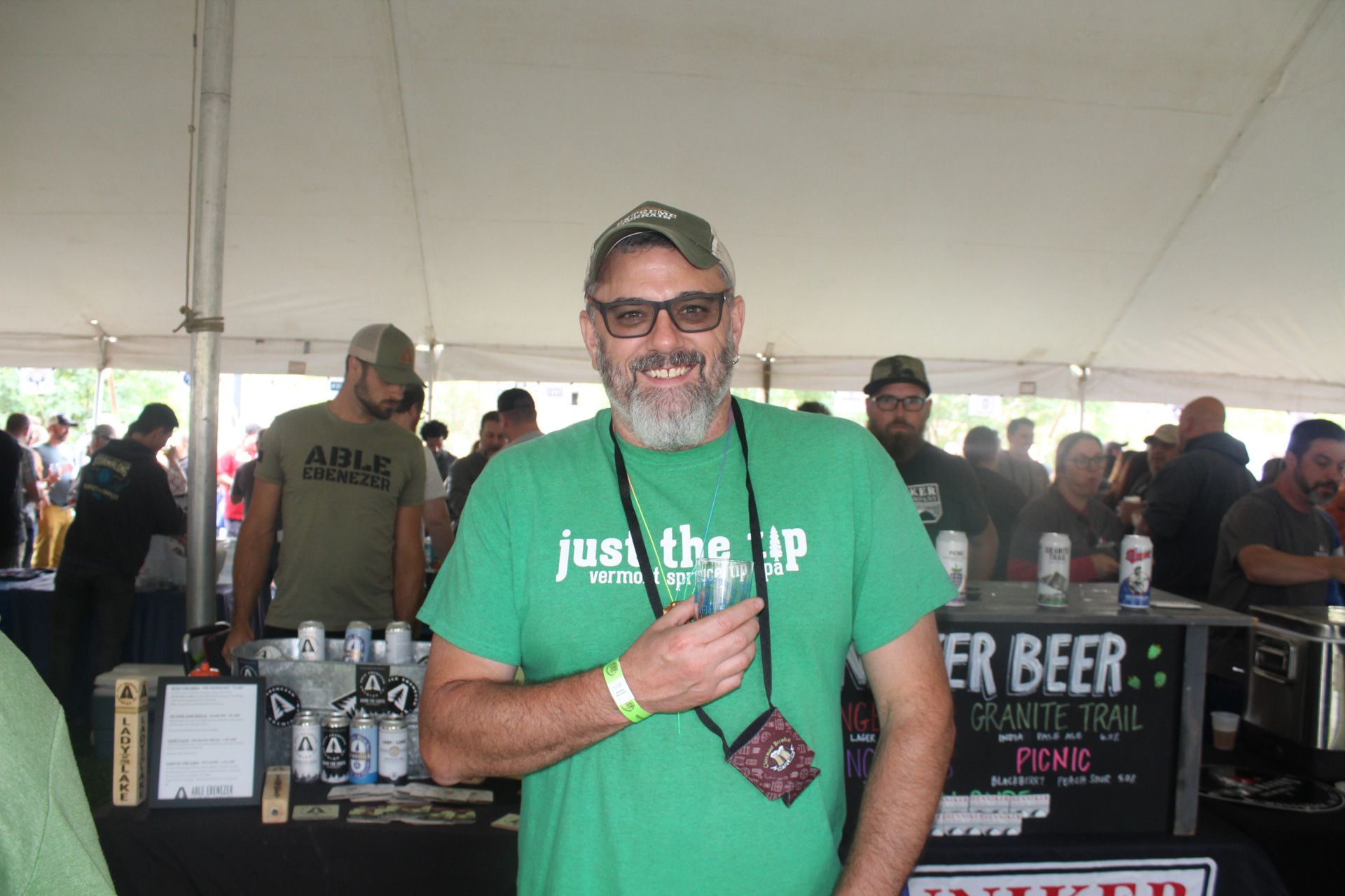 A man in a green shirt is holding a glass of beer.