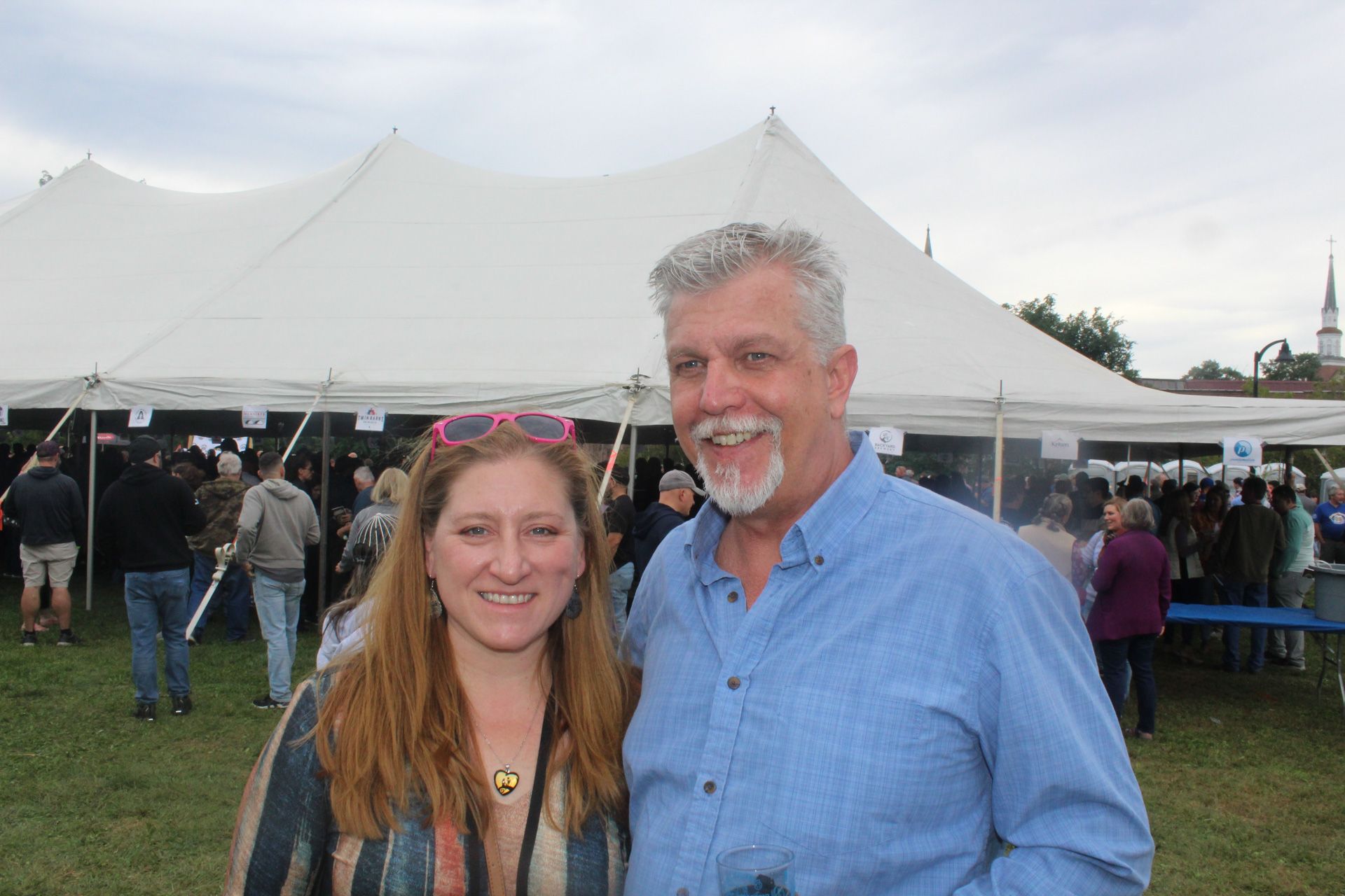 A man and a woman are posing for a picture in front of a tent.