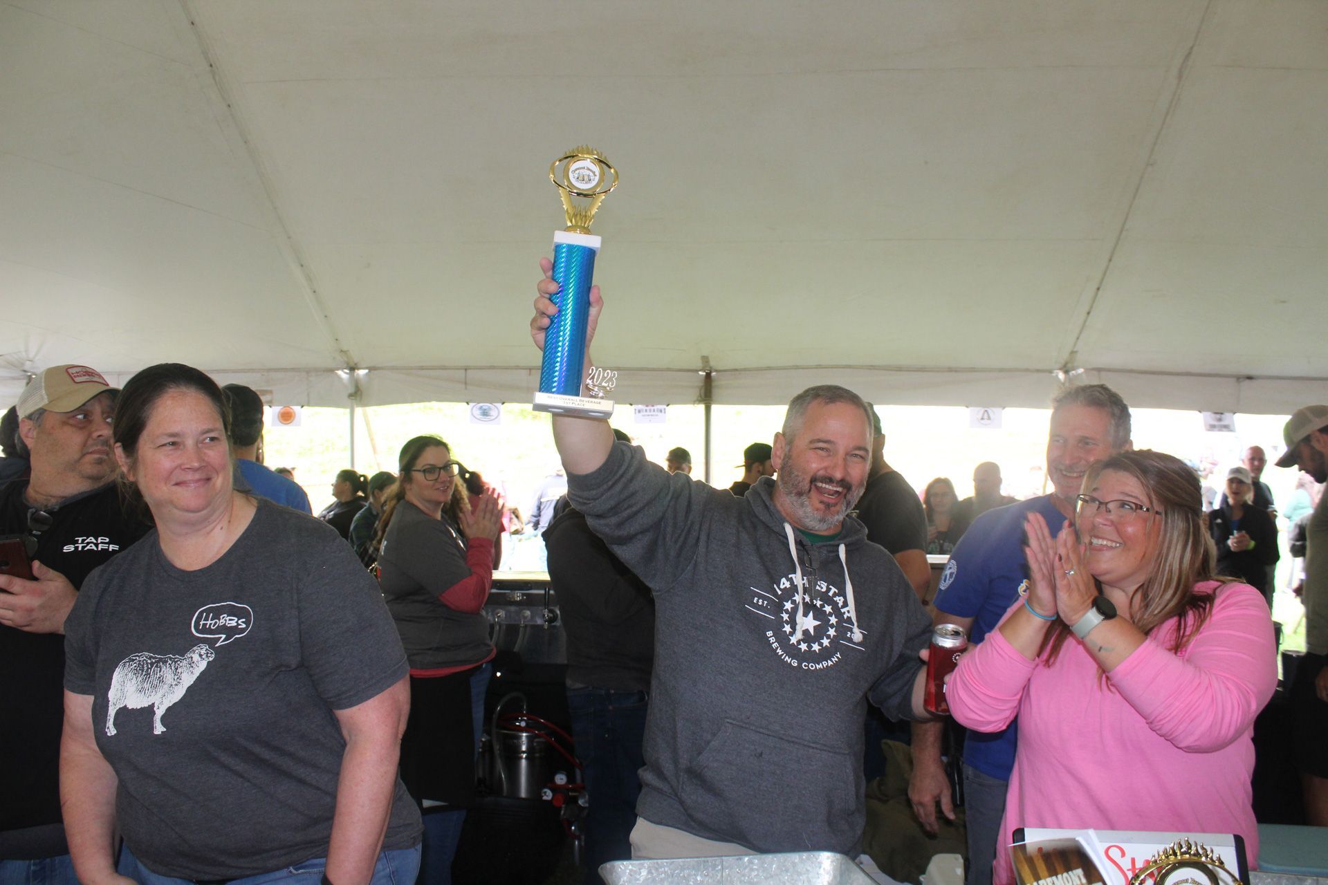 A man is holding a trophy in front of a crowd of people.