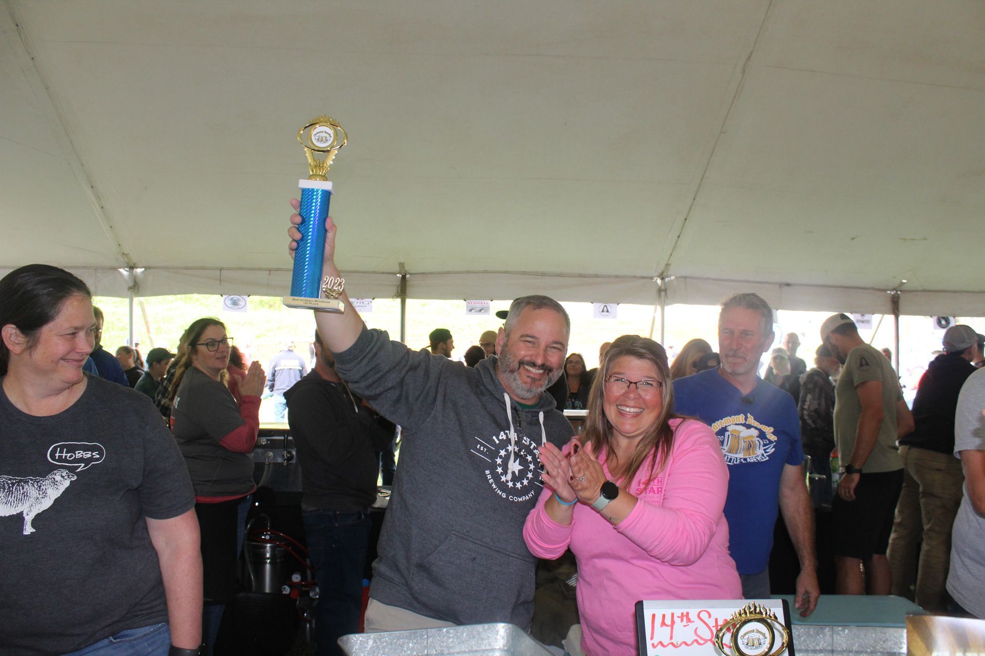 A man is holding a trophy in front of a crowd of people.