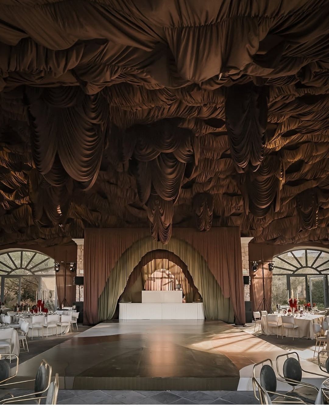 Novia en suelo de piedra con ramo en pasillo rústico de arcos.