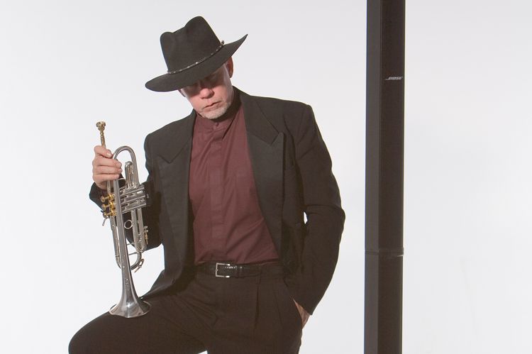 A man in a suit and hat is holding a trumpet