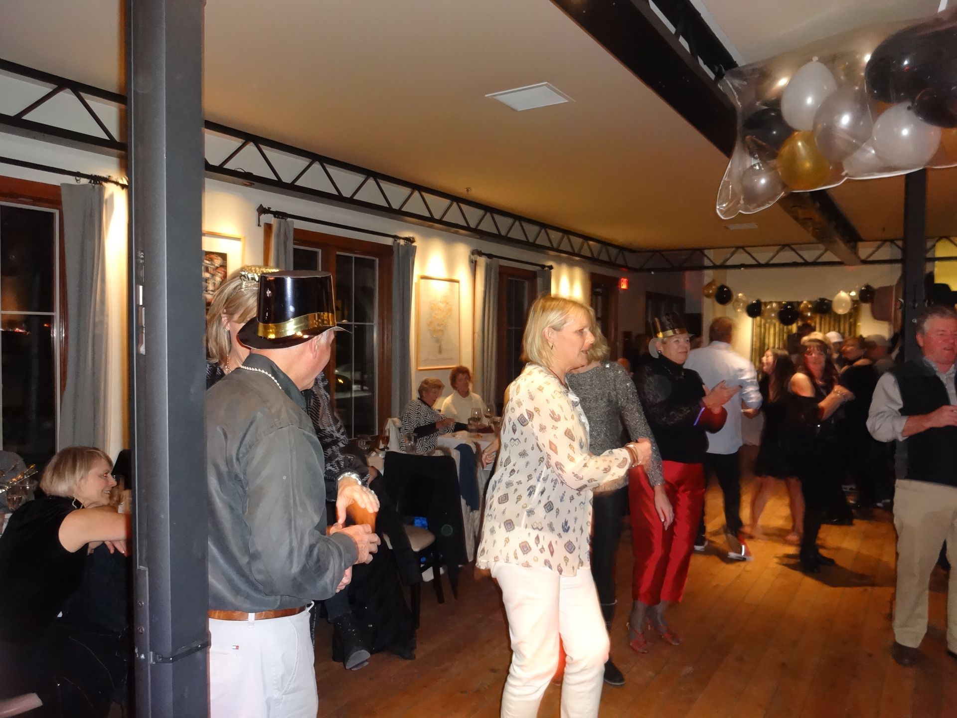 A group of people are dancing in a room with balloons hanging from the ceiling