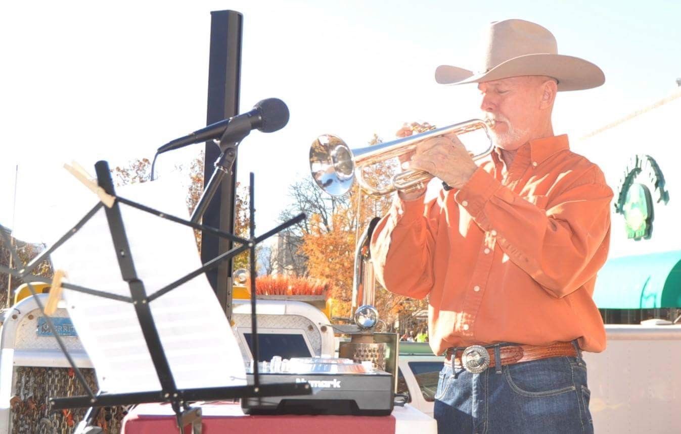 A man in a cowboy hat is playing a trumpet