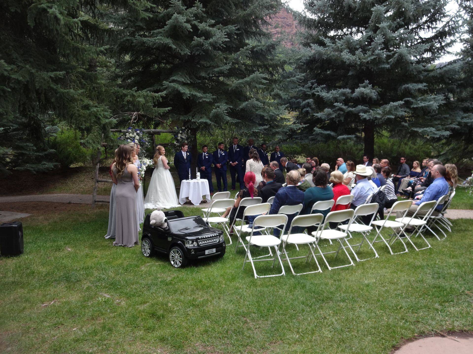A bride and groom are standing in front of a crowd of people at a wedding ceremony.