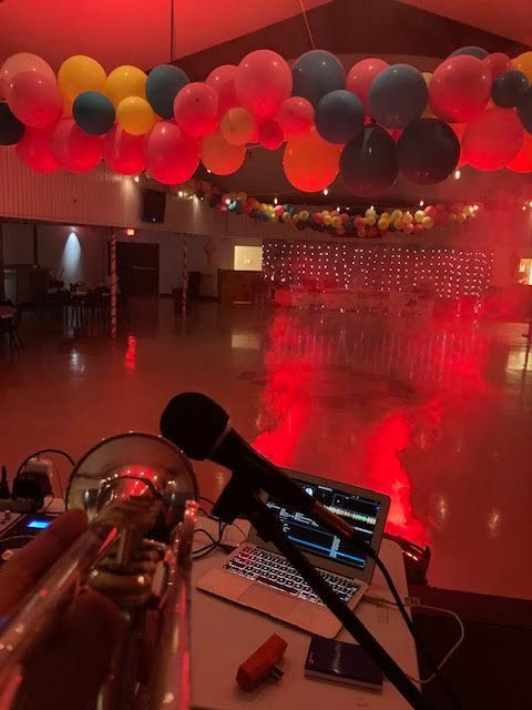 A microphone sits in front of a laptop in a room with balloons hanging from the ceiling