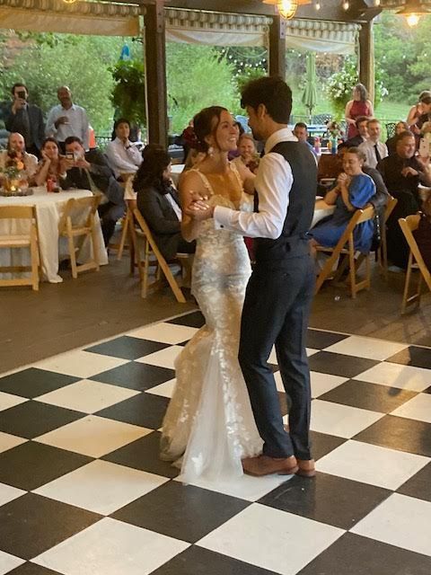 A bride and groom are dancing on a checkered dance floor