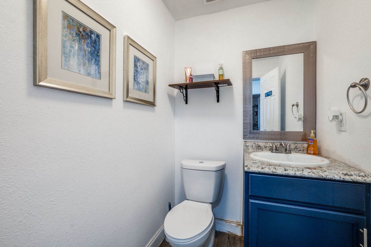 A bathroom with a toilet , sink and mirror.