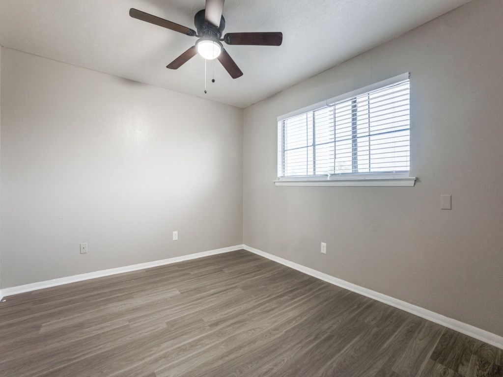 An empty bedroom with a ceiling fan and a window.