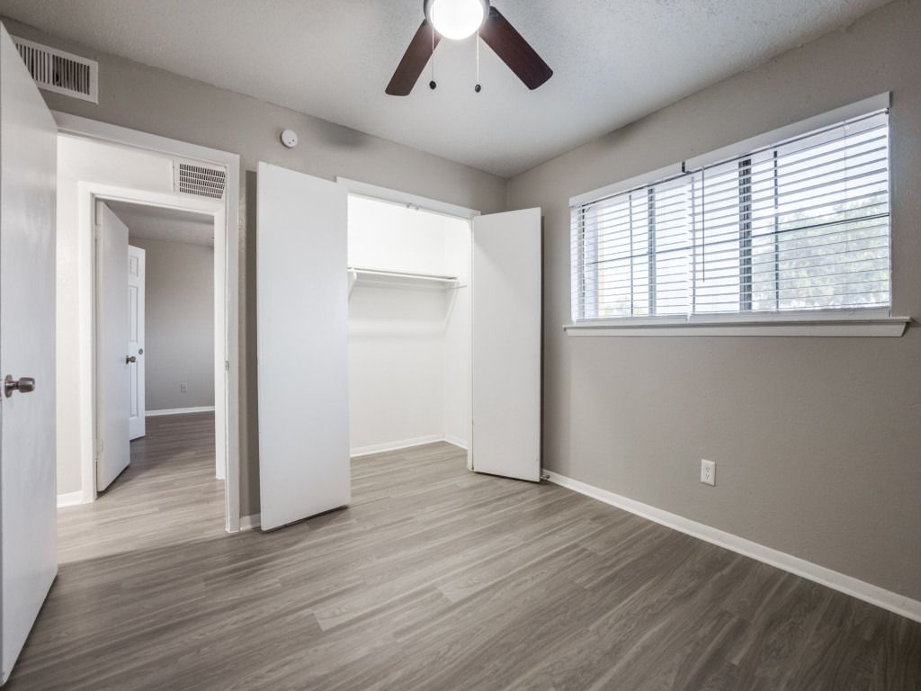 An empty bedroom with a ceiling fan and a window.