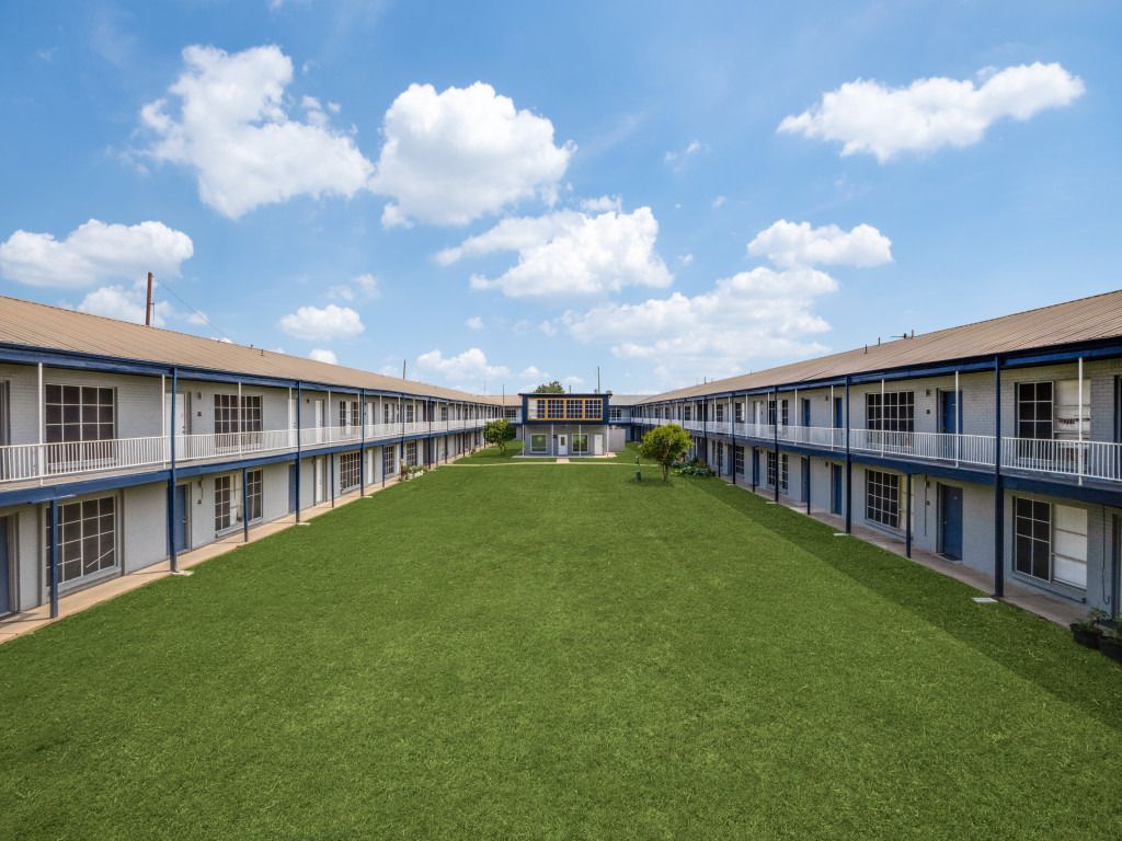 An artist 's impression of a hotel with a large lawn in front of it.