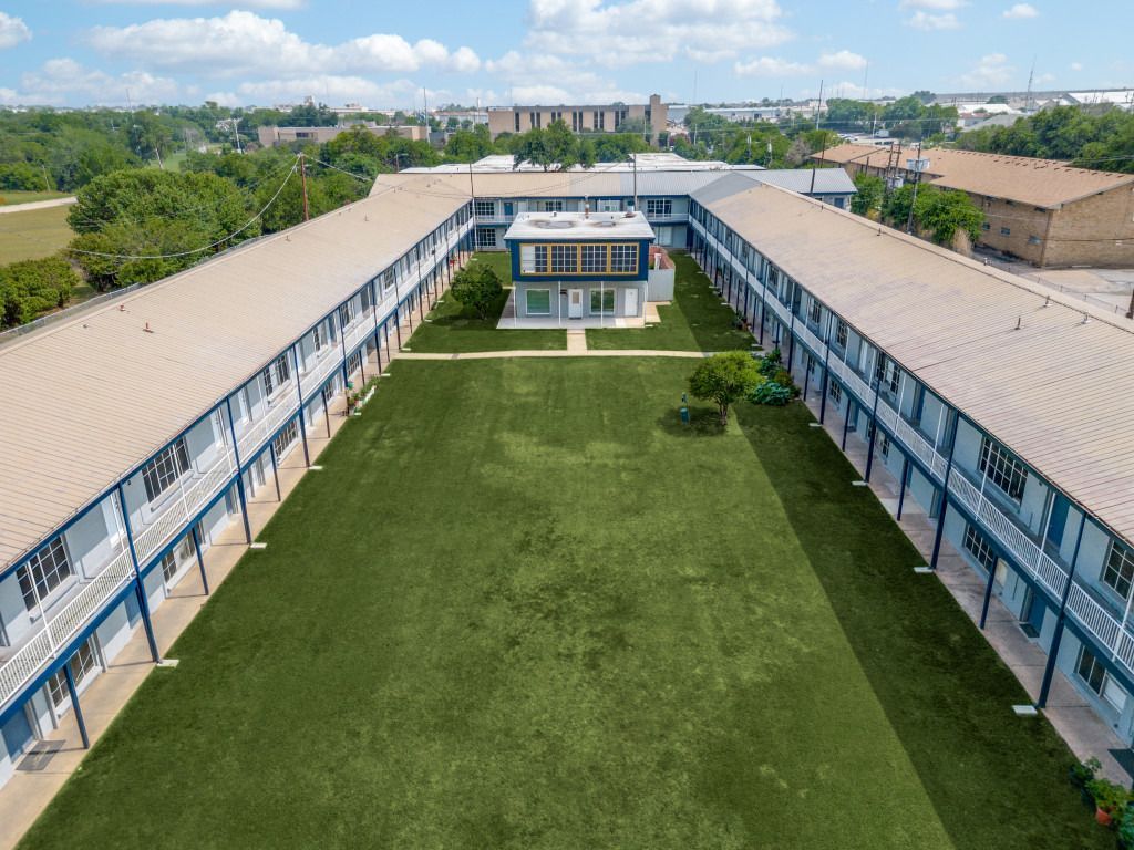 An aerial view of a large apartment building with a large lawn in the middle.