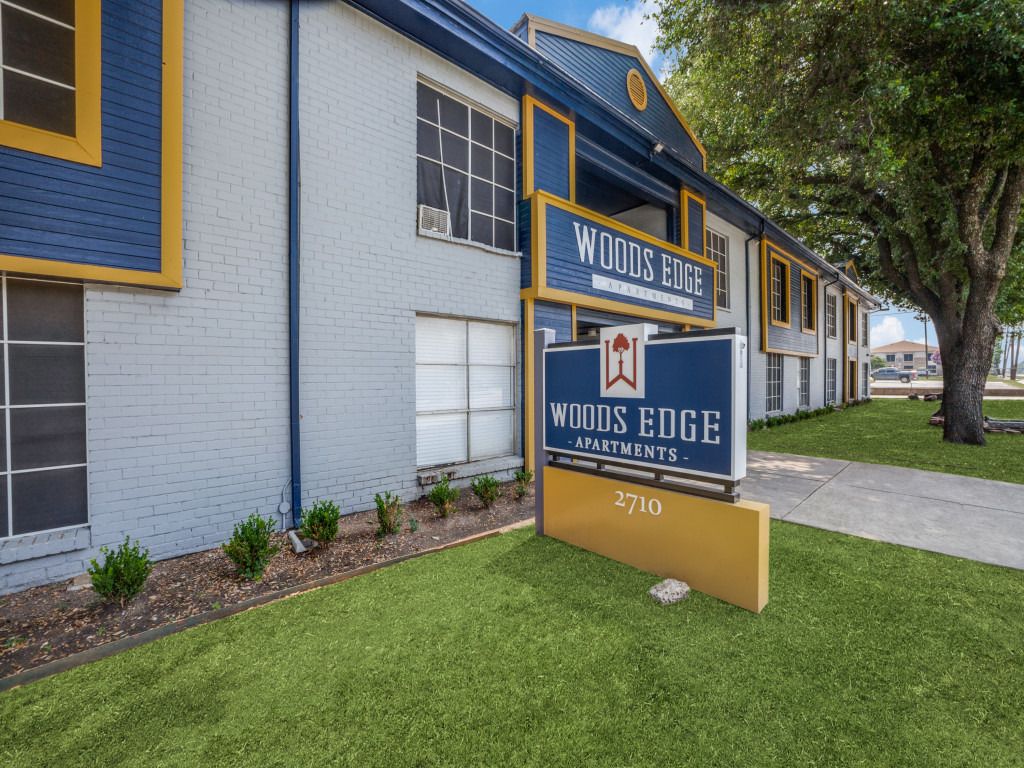 A blue and yellow apartment building with a sign in front of it.